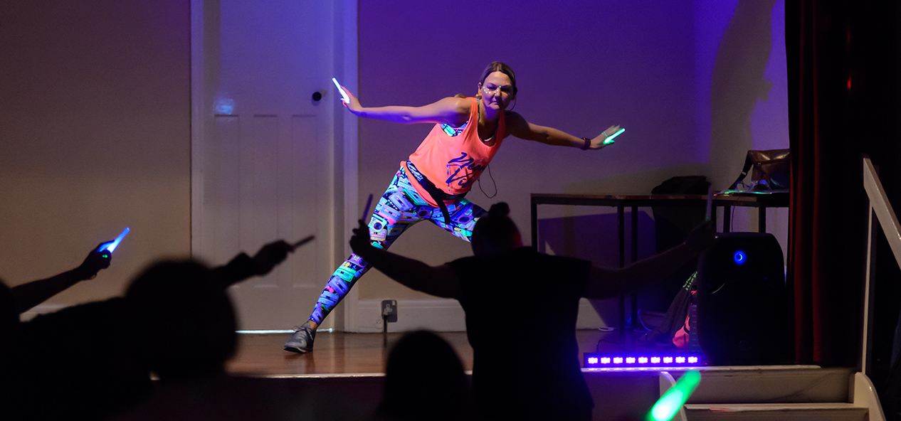 An instructor leads a neon, glow in the dark, dance fitness class