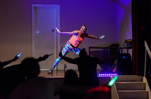 An instructor leads a neon, glow in the dark, dance fitness class