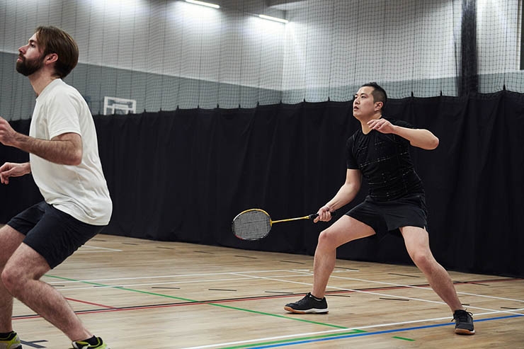 Two men receive the shuttlecock when playing badminton doubles