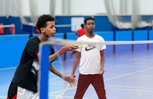 Two boys play badminton in a school PE lesson