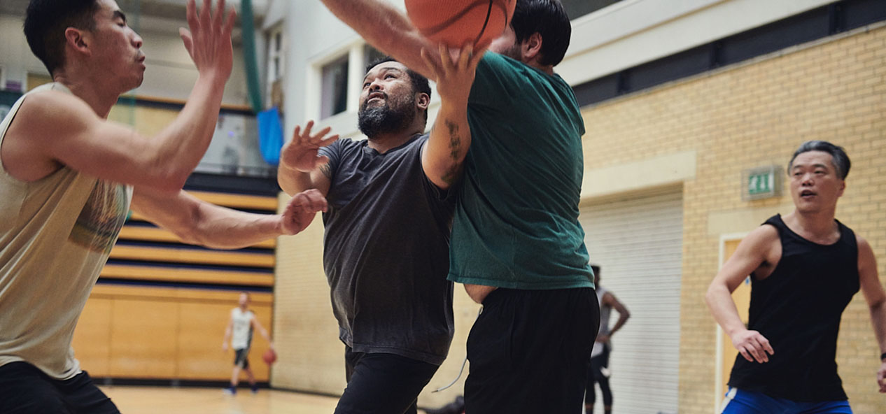 Four men play basketball in a sports hall