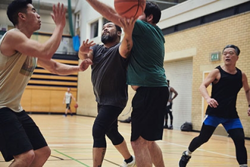 Four men play basketball in a sports hall