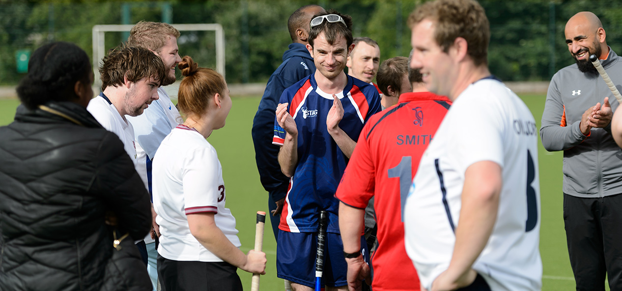 A group of hockey players talking on the field after a game.