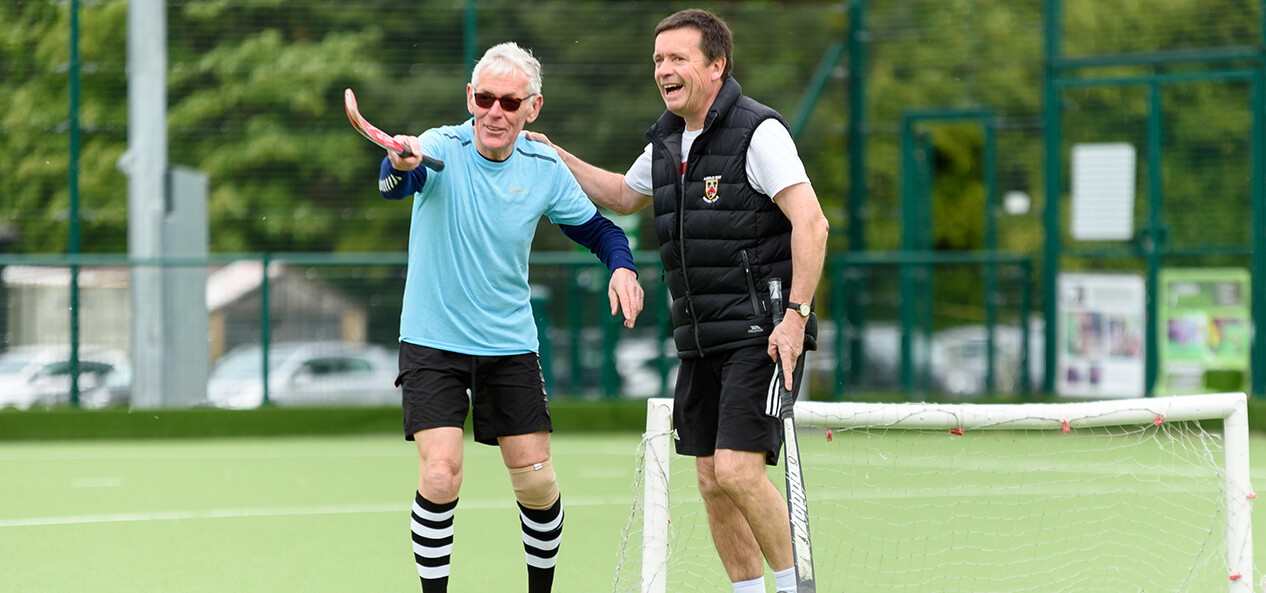 Two men laughing during a game of hockey.