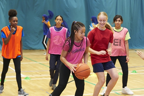 A group of girls play basketball in a sports hall