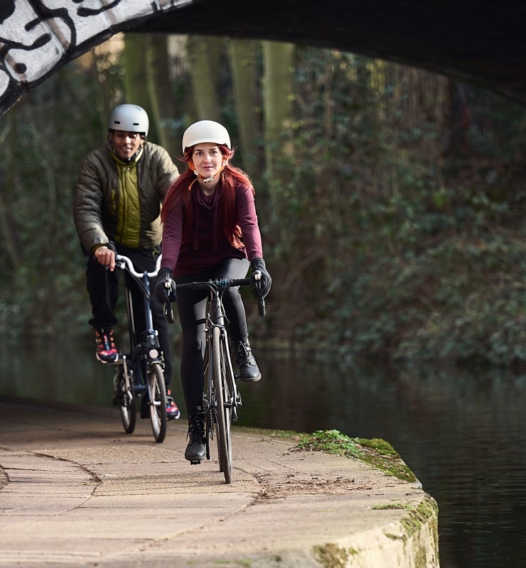 A woman and man cycling on a canal towpath.