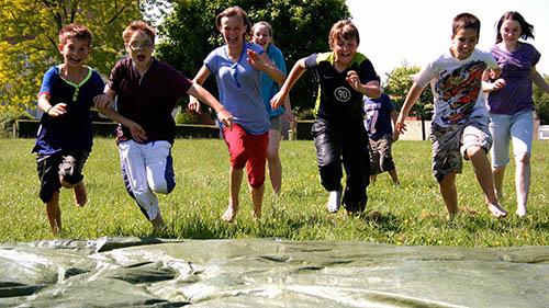 A group of children run towards the camera in a park