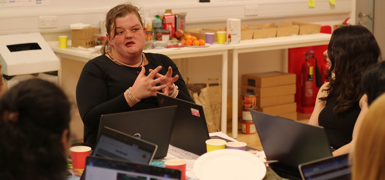 A group of women seat around a table on their computers discussing ideas to reduce inequality.