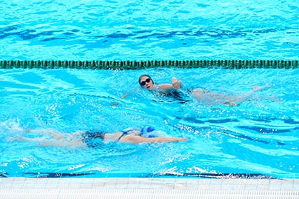 Two people swim lengths in a swimming pool