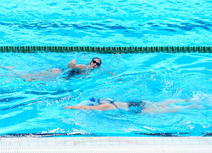 Two people swim lengths in a swimming pool