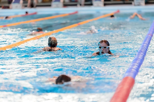 People swim in lanes in an indoor swimming pool