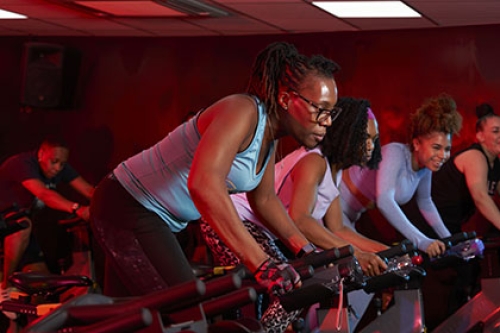 A group of women take part in a spin class at a gym.