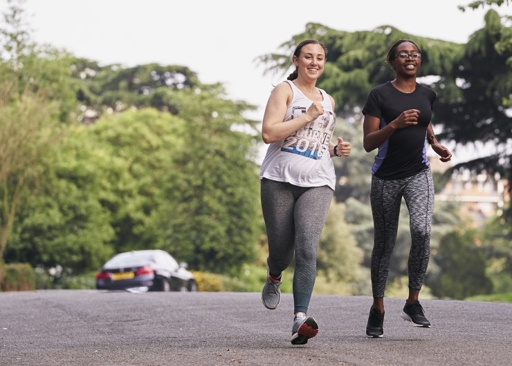 Two women jog side by side down a road.