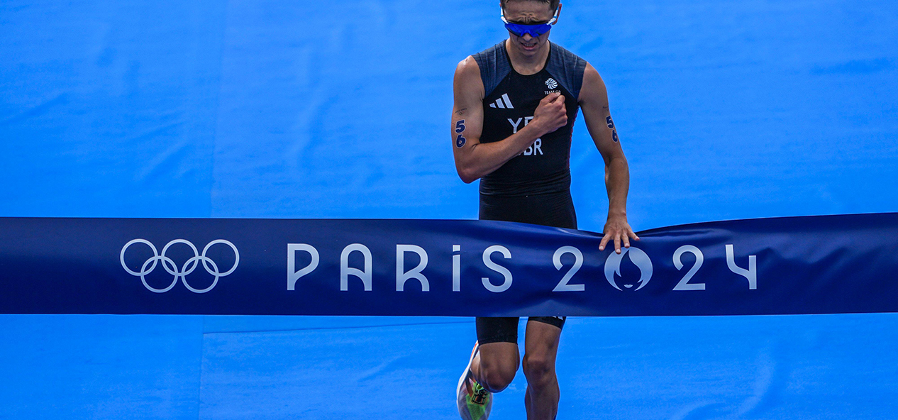 British triathlete Alex Yee thumps his chest as he crosses the line at Paris 2024 to win Olympic gold.