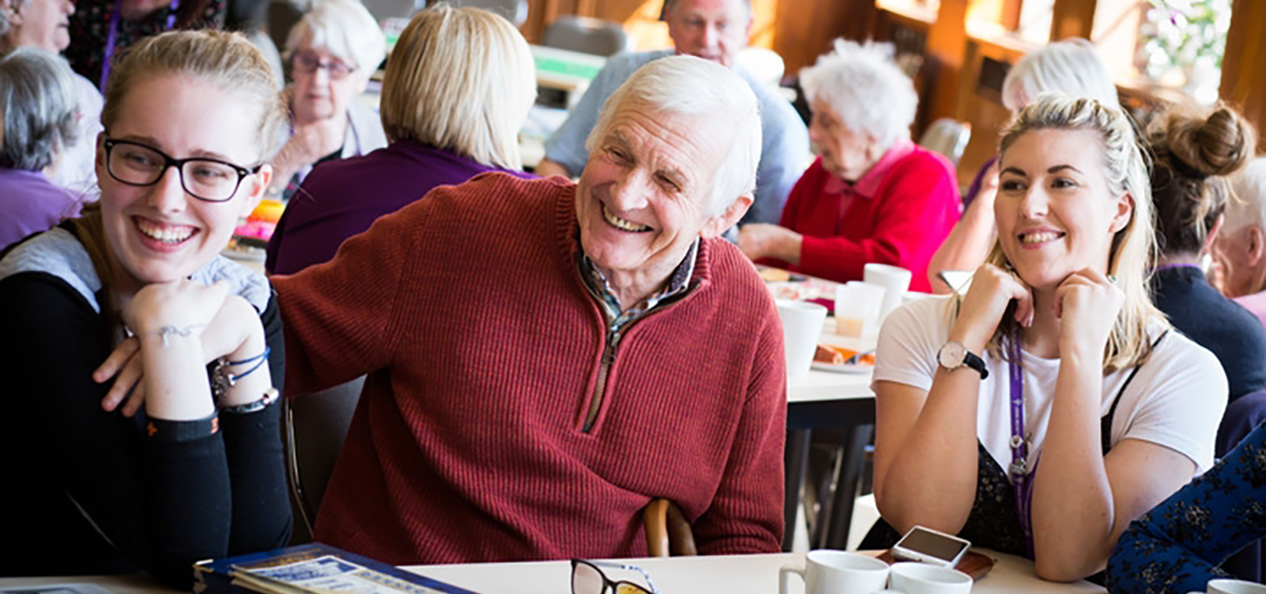 A group of people sit around a table in a care home