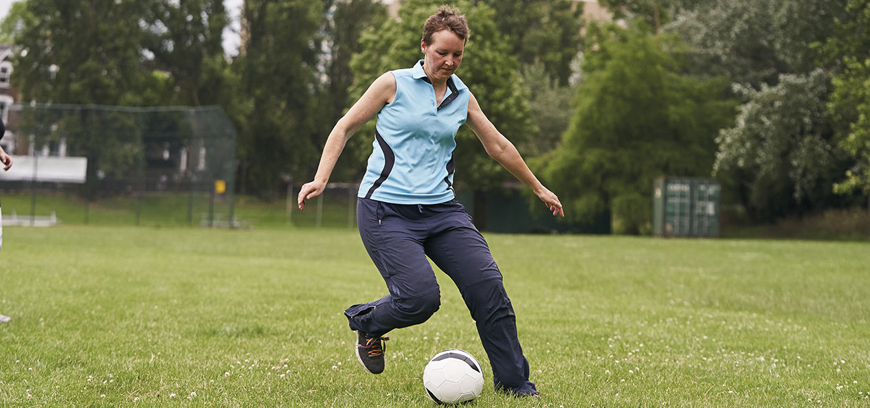 A woman playing football in the park