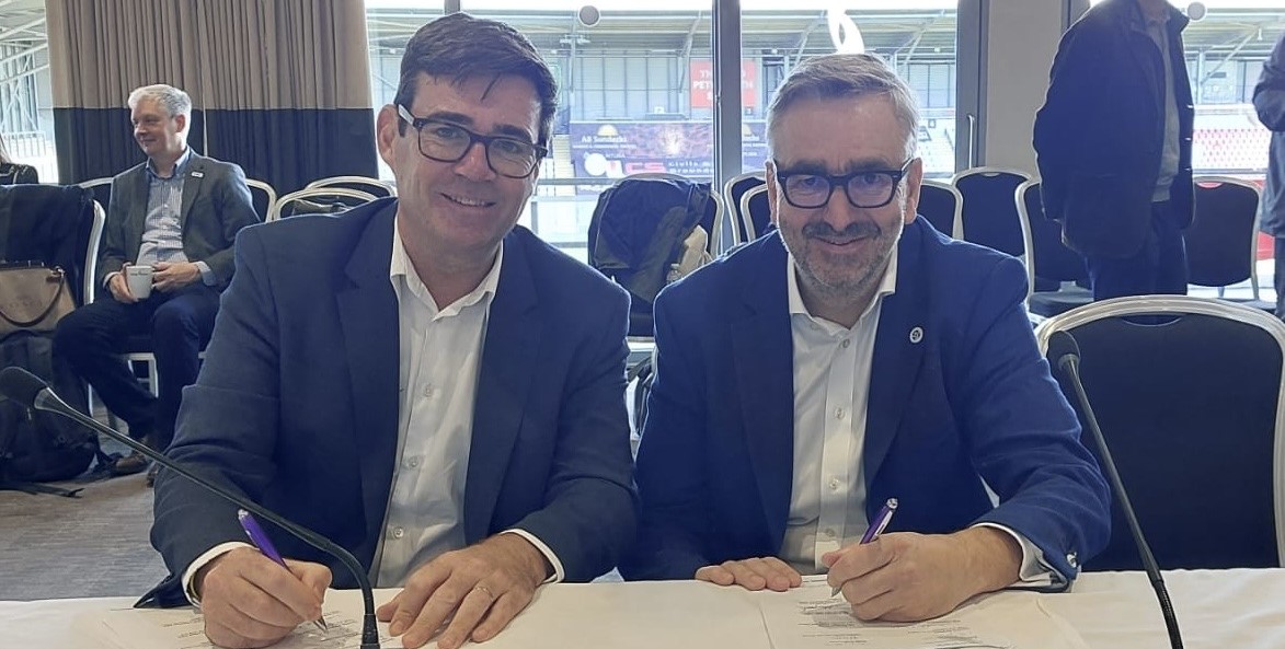 Greater Manchester mayor Andy Burnham and Sport England chief executive Tim Hollingsworth sign a memorandum of understanding while sat at a table