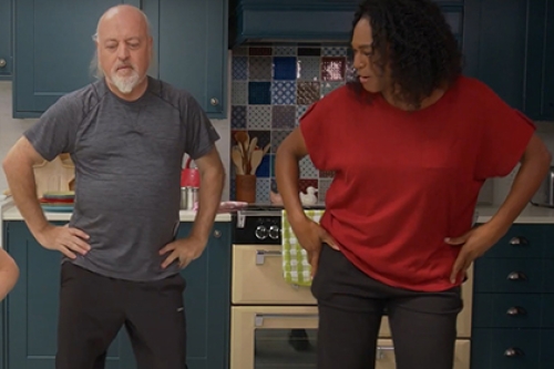 Bill Bailey and an instructor perform hip circles in a kitchen