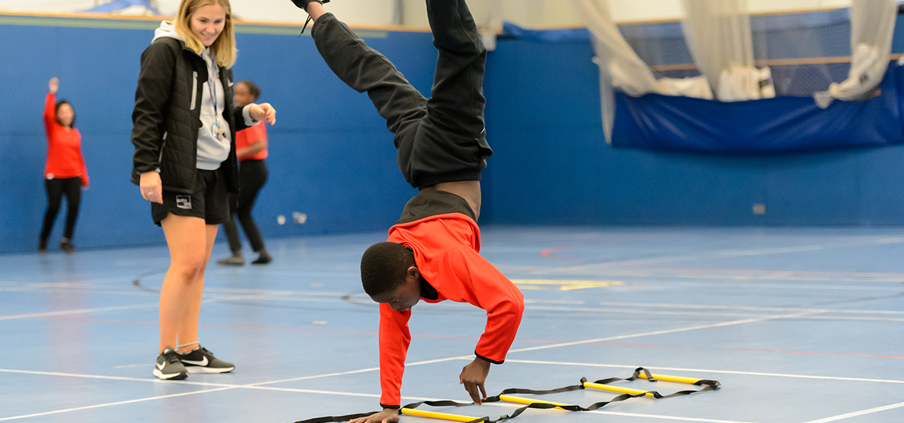 A boy performs a cartwheel in a school PE lesson