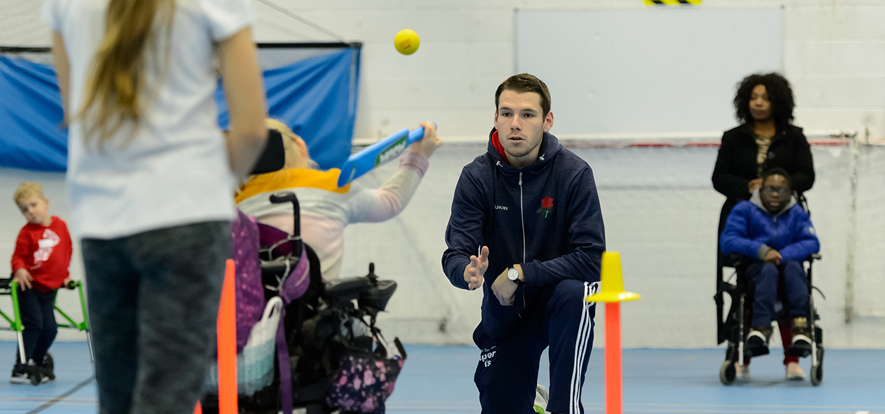 A cricket coaching session takes place in a school hall