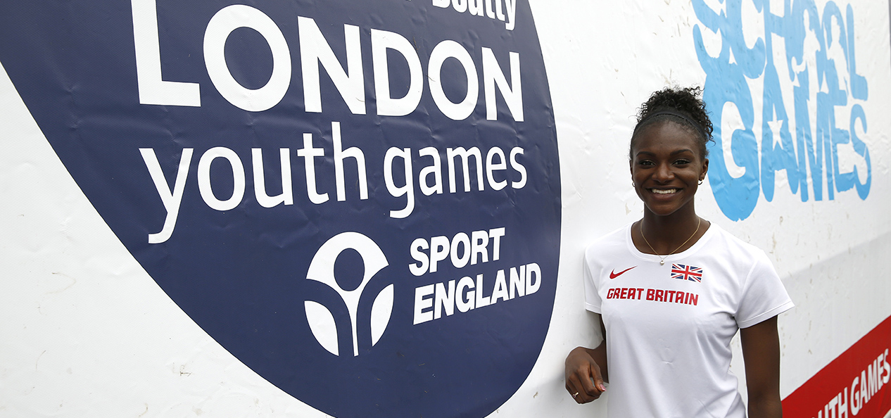 Dina Asher-Smith at the 2015 London Youth Games, standing in front of a sponsor banner