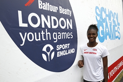 Dina Asher-Smith at the 2015 London Youth Games, standing in front of a sponsor banner