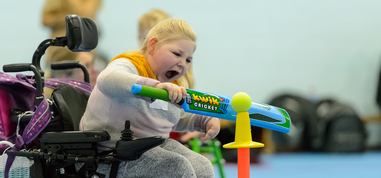 A young girl plays cricket in a wheelchair