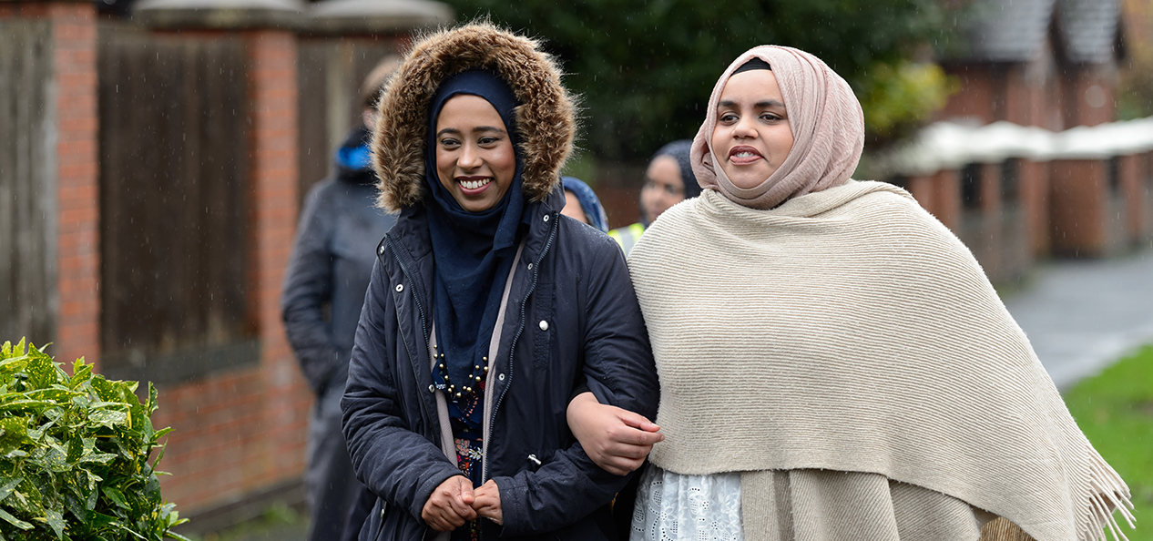 Two women walking arm in arm.