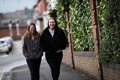 Two young women laugh as they walk down a street