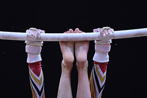 A gymnast works the bar