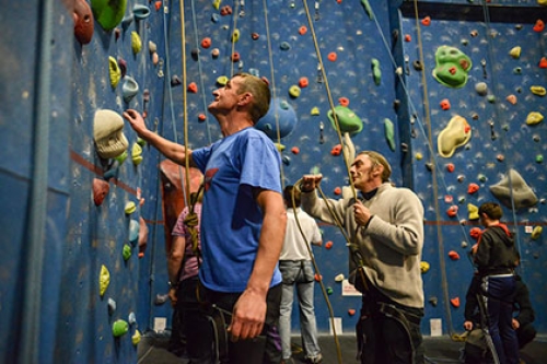 Leaders hold ropes at the foot of a climbing wall