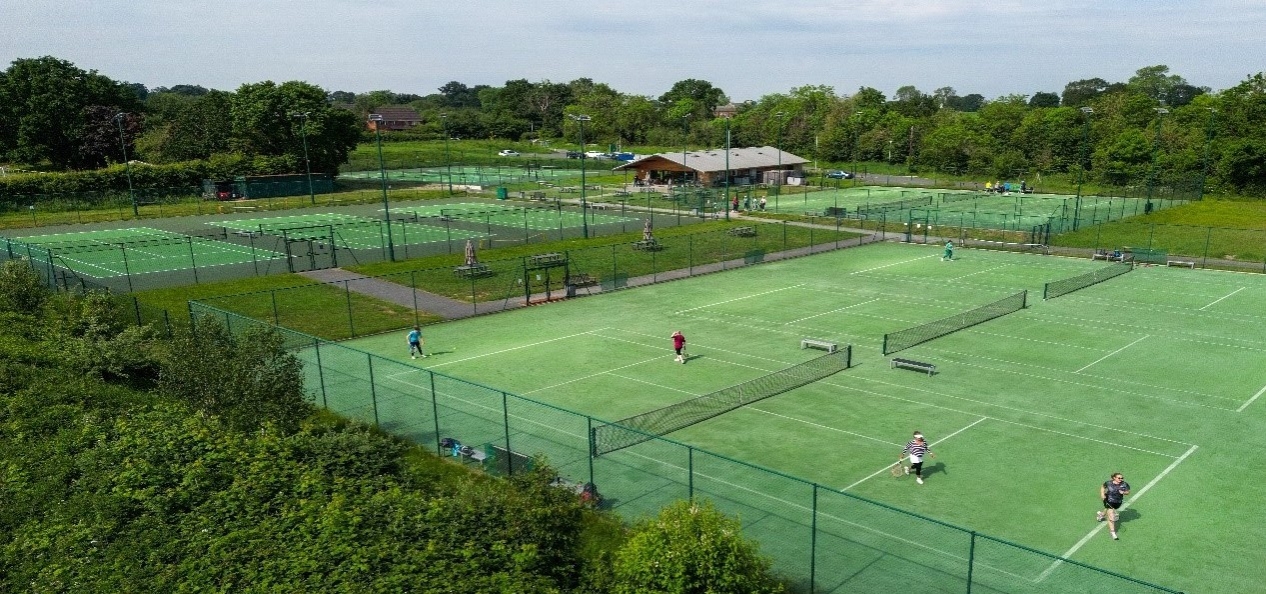 Aerial view of several courts at a tennis club, surrounded by trees