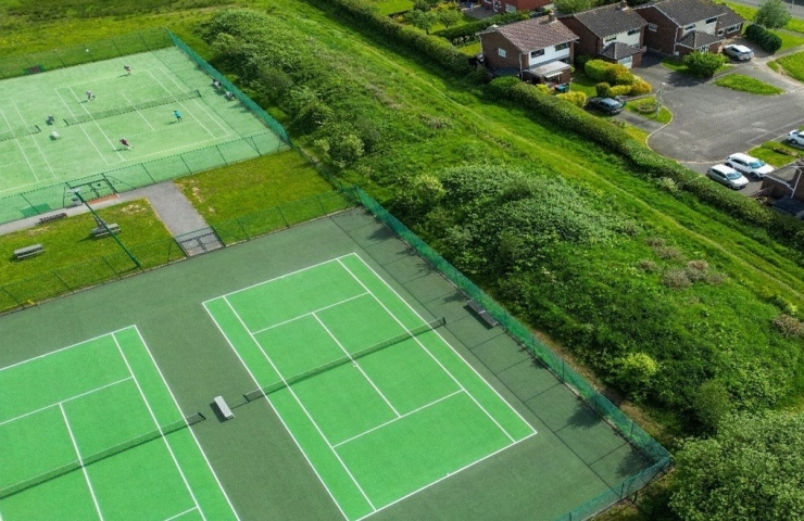 Aerial view of several courts at a tennis club, surrounded by trees