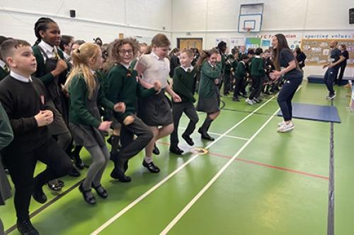 Primary school students take part in an 'Active Assembly' led by a Commonwealth Games athlete as part of a School Games initiative