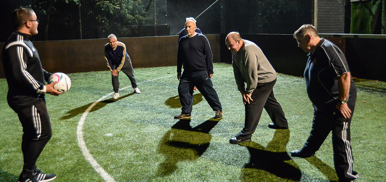 A group of men doing stretches at a walking football session.