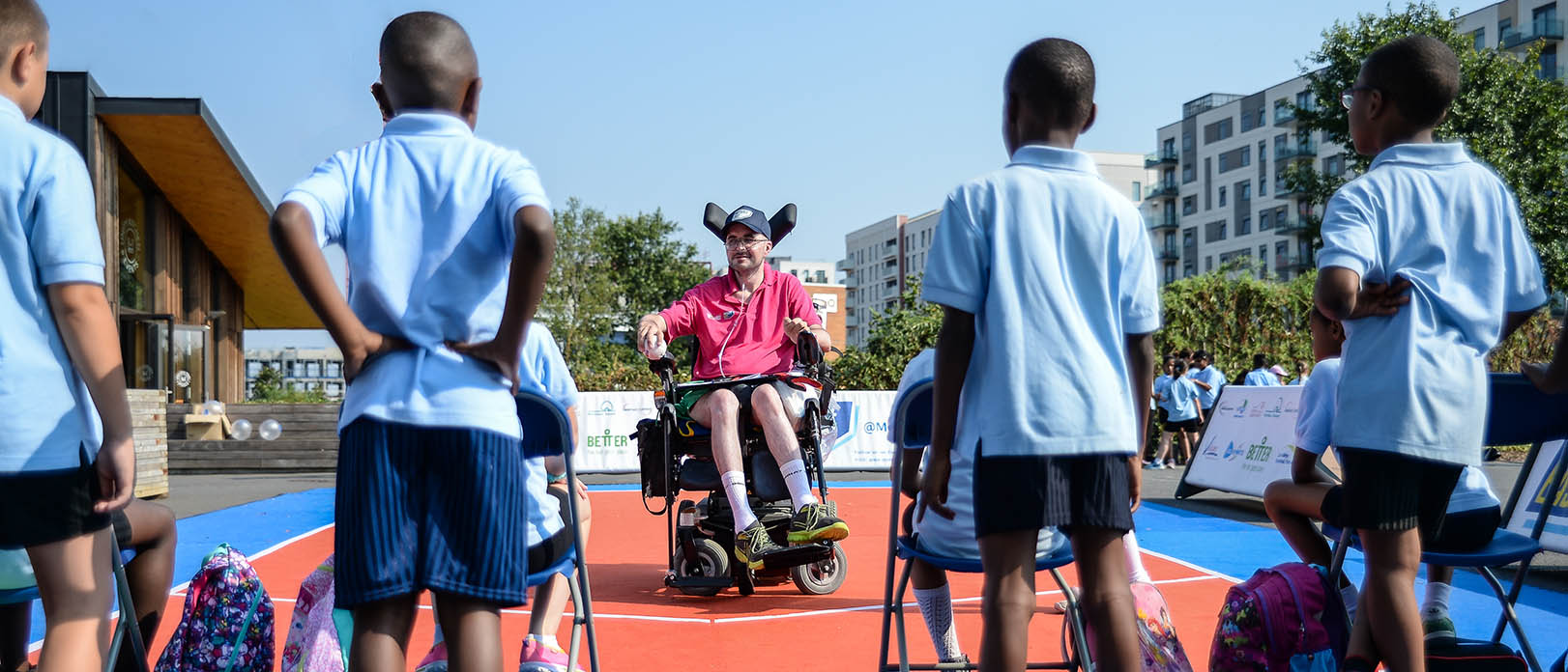 A group of children listen to a coach in a wheelchair