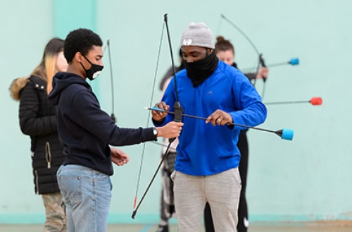 Two boys set up for archery using large cushions instead of arrow heads