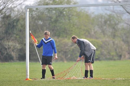 Players set up the nets and corner flags for a football match