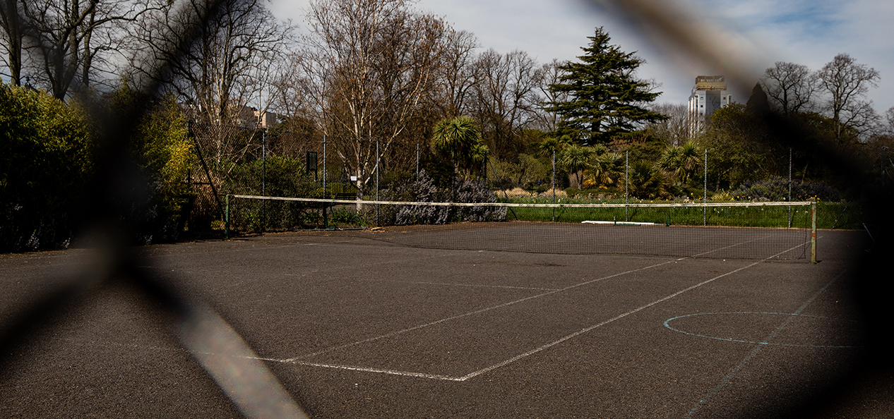 An empty tennis court captured through a wire fence.