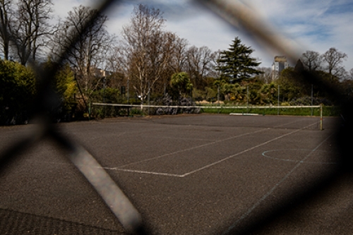 An empty tennis court captured through a wire fence.