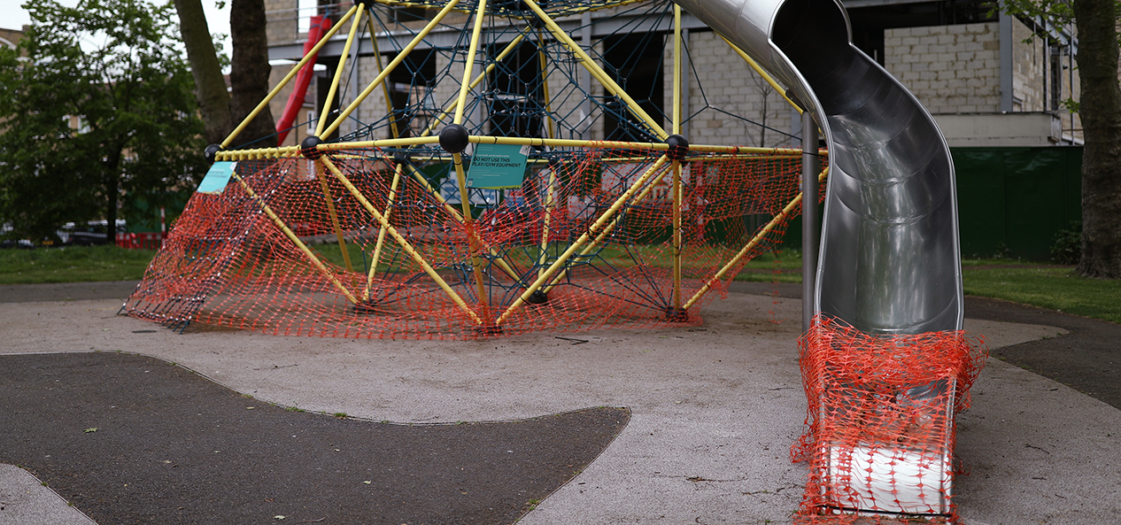 A closed playground with netting over the bottom of a slide