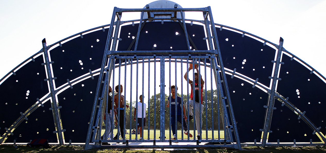 A group of teenagers play basketball in a park.