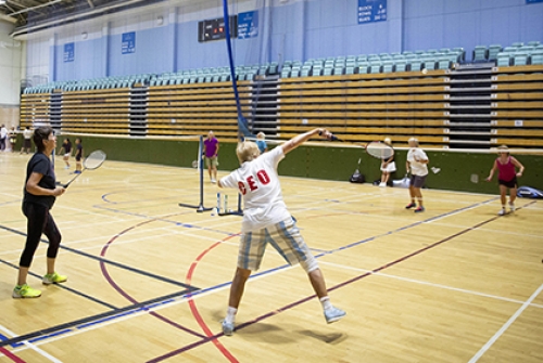 A group of people play badminton in a sports hall.