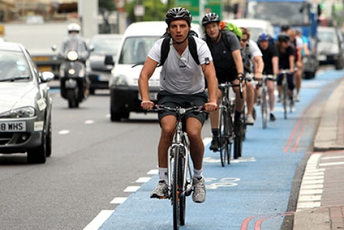 Cyclists ride on a cycle superhighway in London, alongside cars