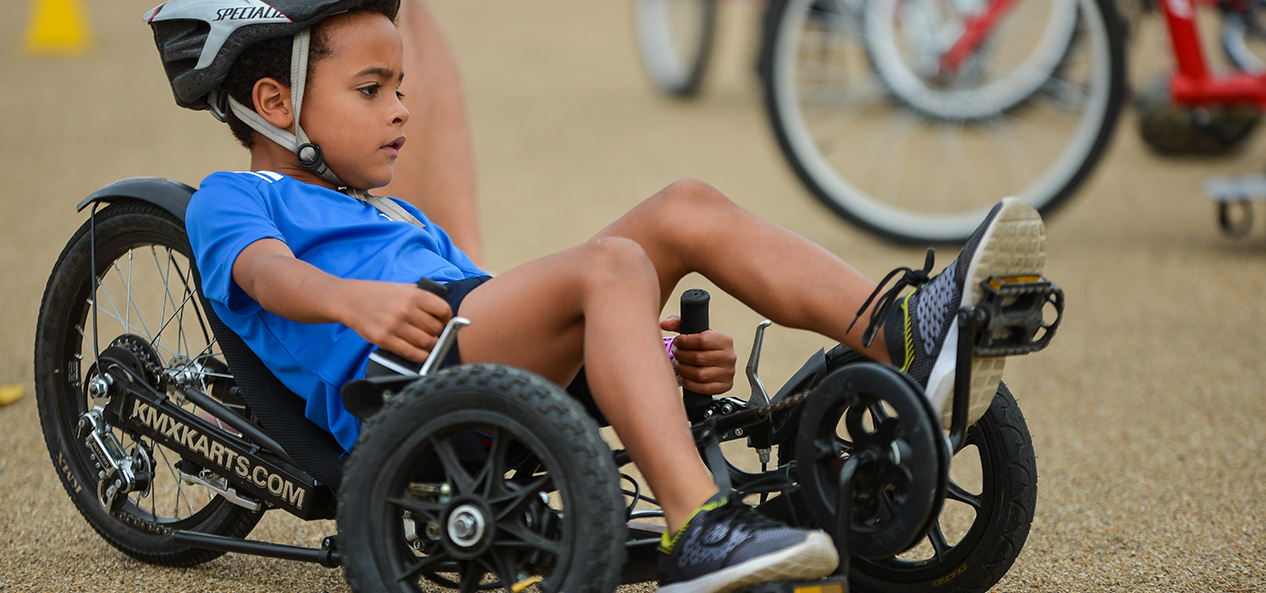 A boy rides an adapted recumbent tricycle