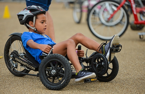 A boy rides an adapted recumbent tricycle