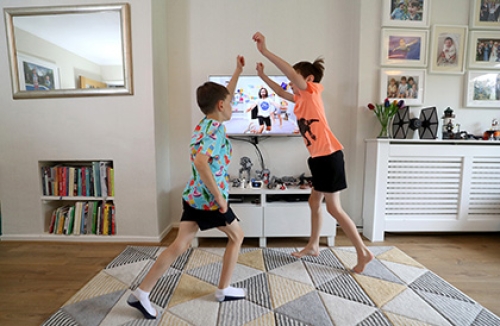 Two boys perform exercise in their living room as part of Joe Wicks' 'PE with Joe' programme.