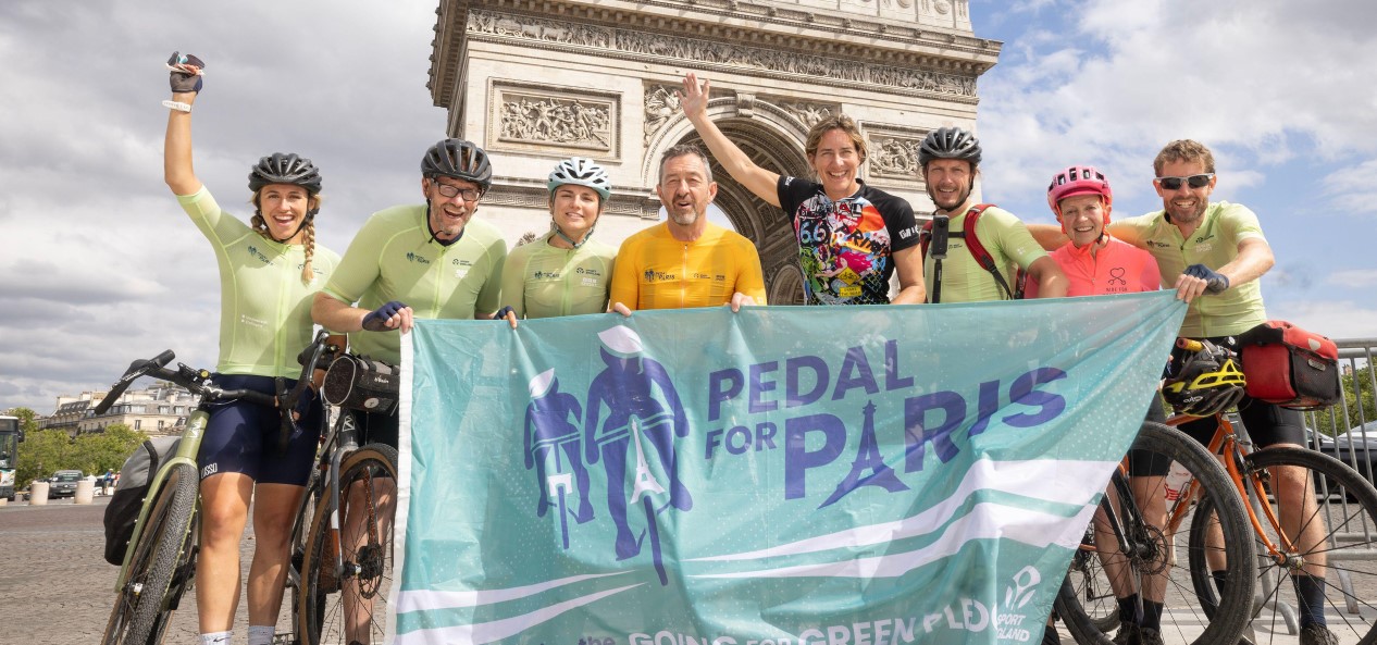 hris Boardman, Dame Katherine Grainger and the Pedal for Paris cycle team pose with their bikes, a flag and arms raised in front of the Arc de Triomphe.