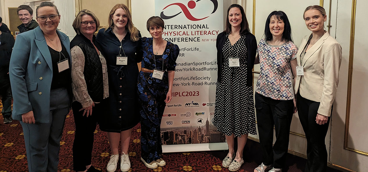 Sport England Charlie Crane and Georgina Howe stand by the International Physical Literacy Conference banner in New York.