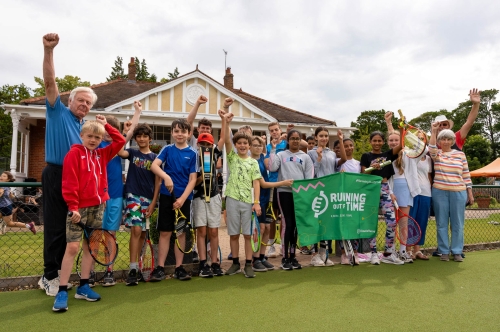 People of varying ages hold a flag saying 'Running out of time' in front of a clubhouse at a tennis club